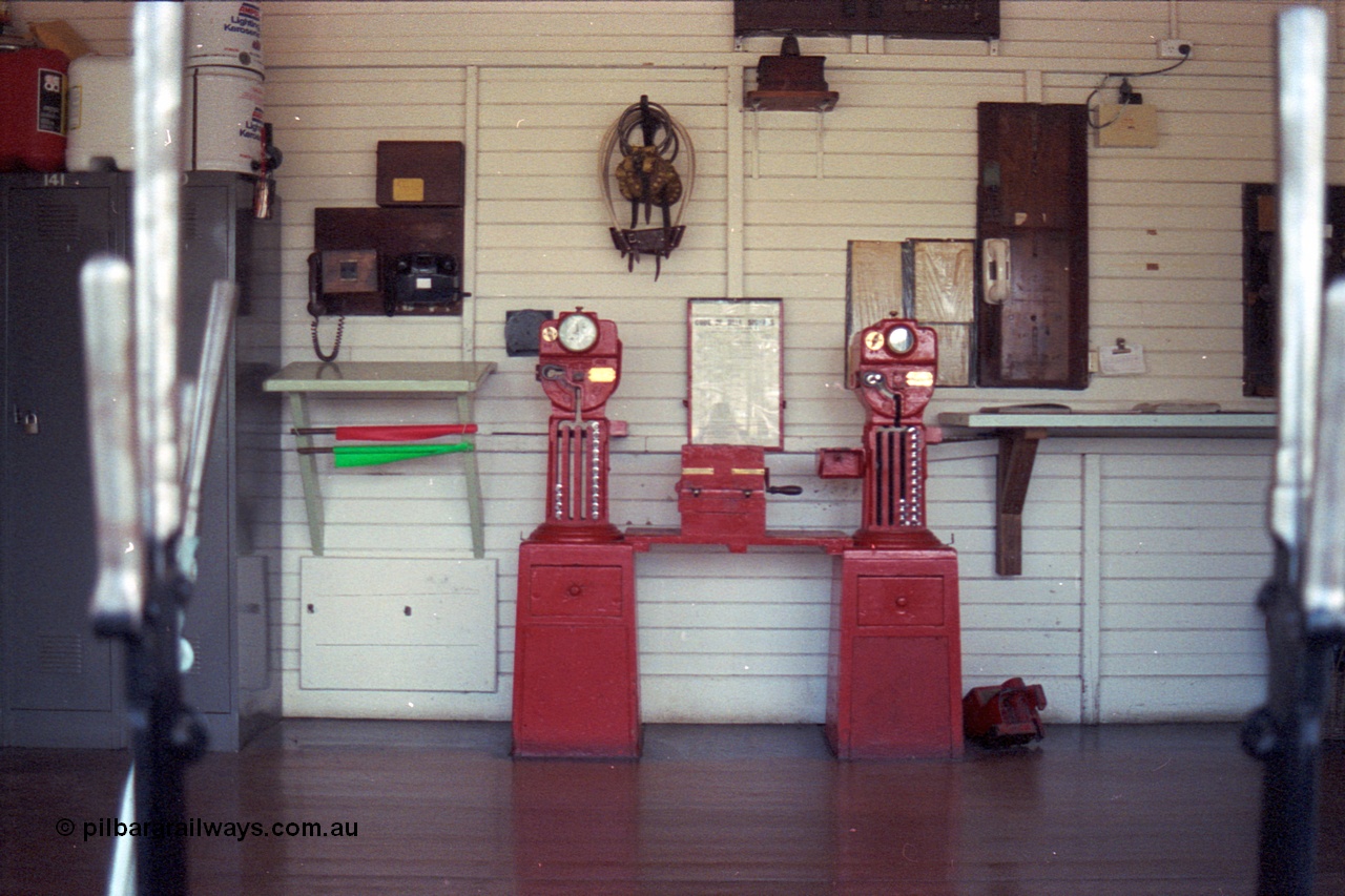 104-15
Buangor, view inside signal box through window, miniature electric staff exchange machines, Buangor to Ararat machine on the left and Trawalla to Buangor machine on the right, control telephones, chart of bell codes, tins of kerosene, exchange hoops and other paraphernalia for running trains in the 19th century.
