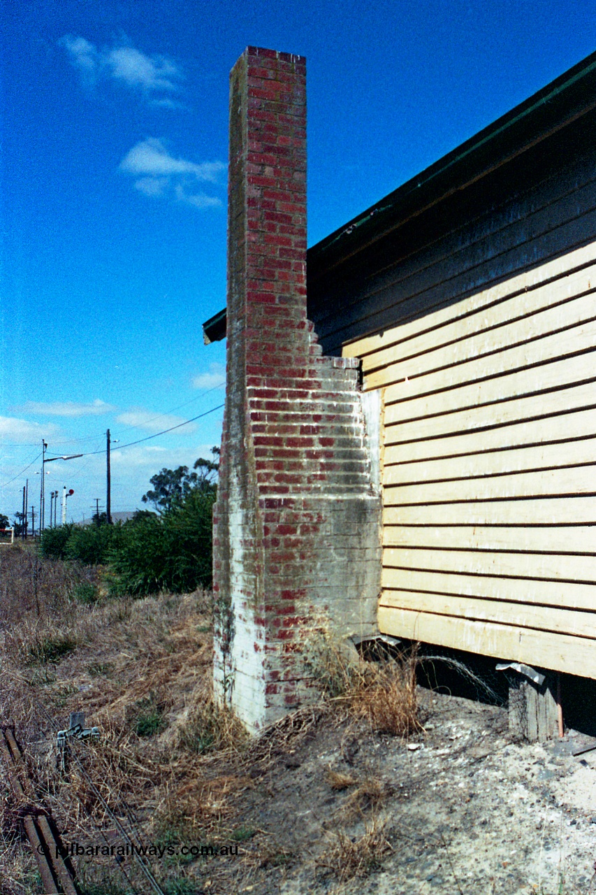 105-16
Wallan, station platform 2 waiting room, brick chimney, rear side elevation, point rodding and signal wires in grass view.
