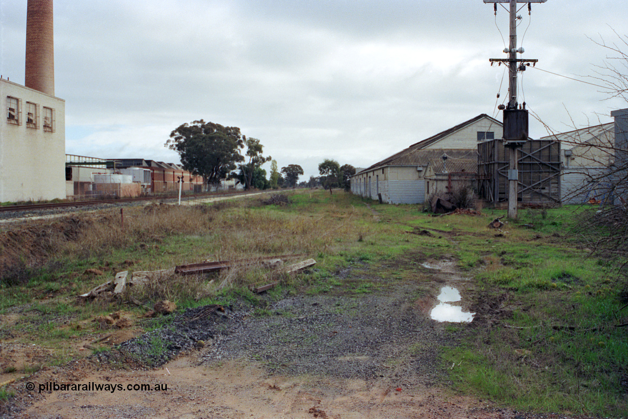 107-04
Kyabram track view, buried rails for Kyabram Fruit Packers siding, Southern Can Company on the left, looking towards Echuca.
