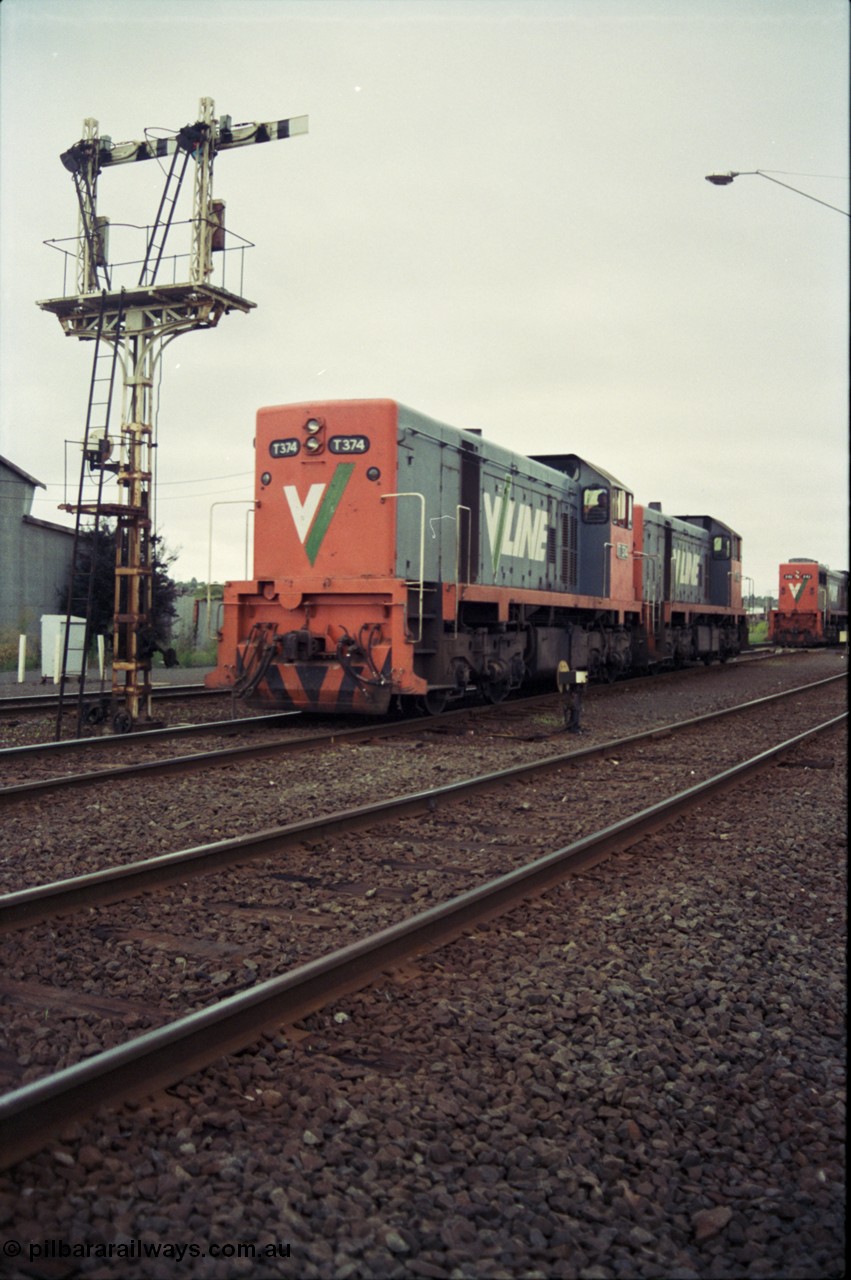 111-08
North Geelong grain arrivals yard, V/Line broad gauge locos T class T 374 Clyde Engineering EMD model G8B serial 64-329 and T class 3?? shunt past ground disc signal 12 pulled off for the move, under semaphore signal post 13, X class X 42 Clyde Engineering EMD model G26C serial 70-705 is still on the up Mt Gambier goods train 9192 at the far right.
Keywords: T-class;T374;Clyde-Engineering-Granville-NSW;EMD;G8B;64-329;