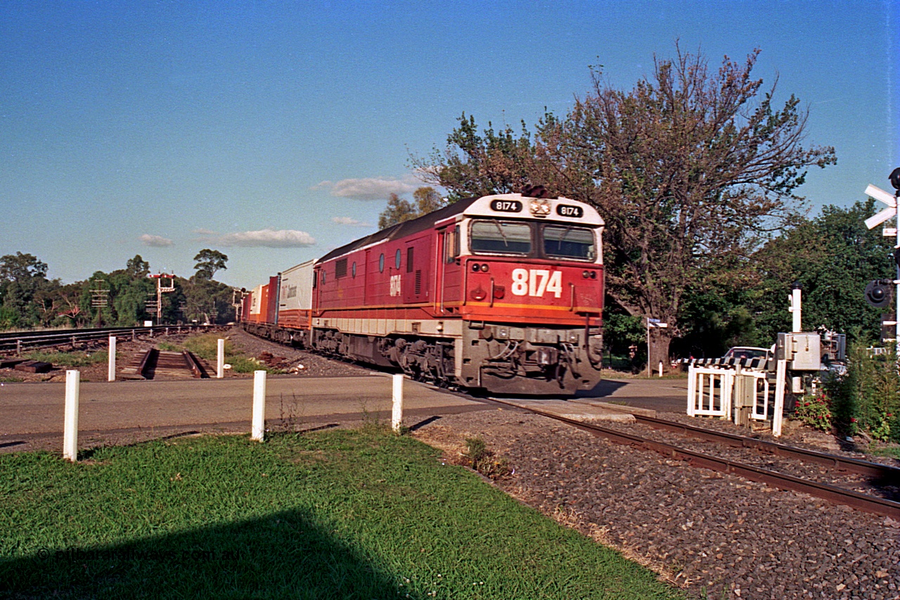 112-11
Violet Town, looking north across Cowslip Street, standard gauge NSWSRA 81 class 8174 Clyde Engineering EMD model JT26C-2SS serial 85-1093 in candy livery with an up goods heads south, station building behind camera, broad gauge track on the left, March 1994.
Keywords: 81-class;8174;Clyde-Engineering-Kelso-NSW;EMD;JT26C-2SS;85-1093;