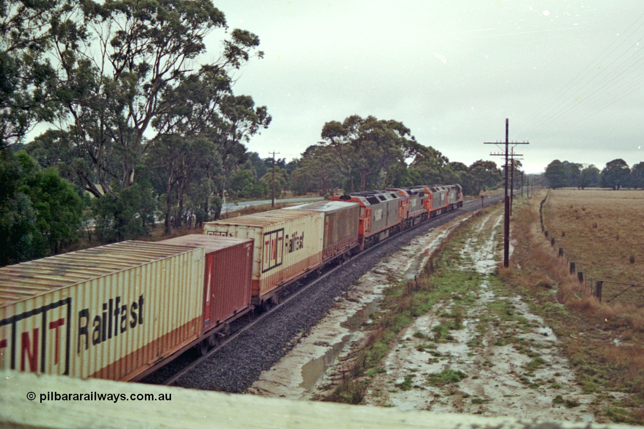 113-14
Near Gordon at Portland Flat road bridge, V/Line broad gauge up Adelaide goods train 9150 behind the quad CGCG combo of C class C 506 Clyde Engineering EMD model GT26C serial 76-829, G class G 538 Clyde Engineering EMD model JT26C-2SS serial 89-1271, C 510 serial 76-833 and G 513 serial 85-1241, in miserable conditions, poor quality, trailing view.
