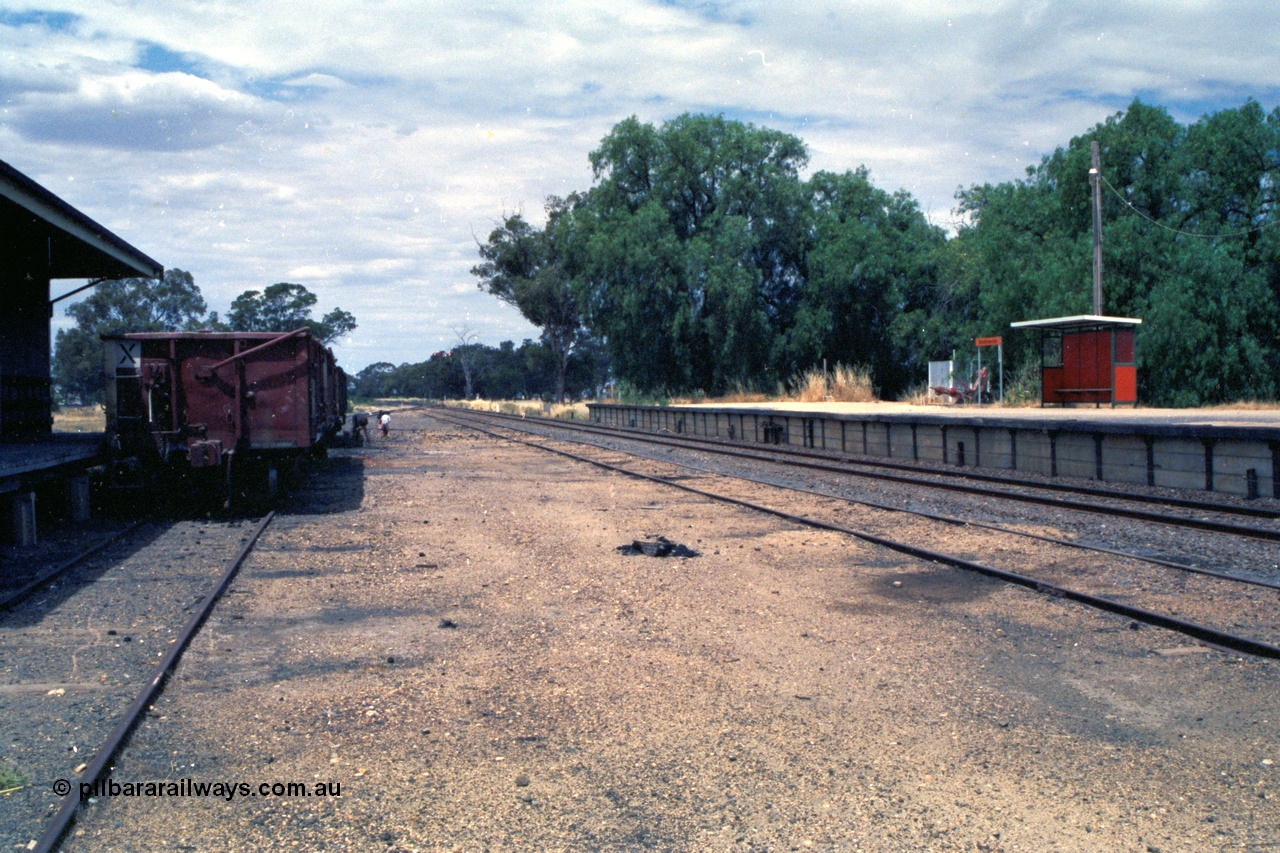 118-04
Strathmerton station yard overview, looking north, platform, bus style waiting shelter, signal bay, people picking coal, V/Line broad gauge VOBX type bogie open waggons.
Keywords: VOBX-type;