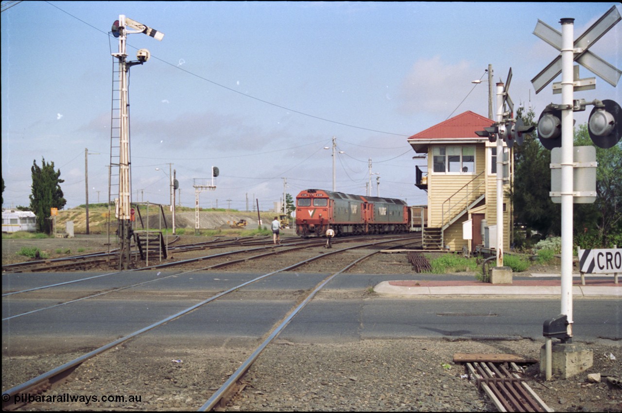 119-10
North Geelong C Box, V/Line broad gauge G classes G 540 Clyde Engineering EMD model JT26C-2SS serial 89-1273 and sister depart with down empty grain train 9125, looking across Separation Street, semaphore signal post 16 is pulled off for move, grade crossing, point rodding, signal box, 2nd person walking to loco with staff for section to Gheringhap.
Keywords: G-class;G540;Clyde-Engineering-Somerton-Victoria;EMD;JT26C-2SS;89-1273;