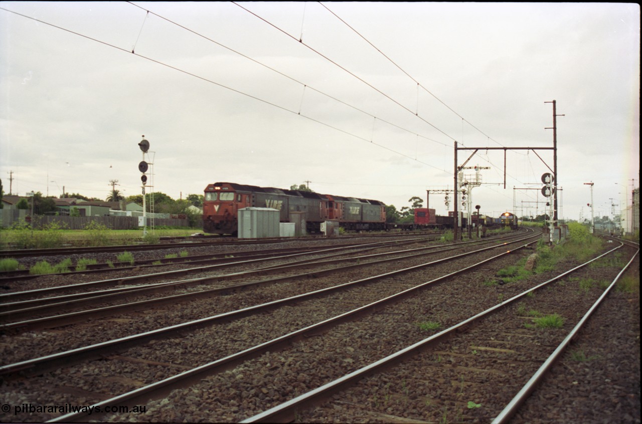 119-16
Sunshine, looking towards Tottenham, broad gauge down goods train 9149 is passed by down standard gauge goods train, V/Line G class locos, looking across all tracks.
