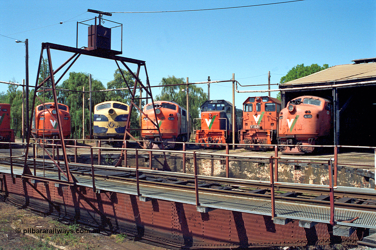 122-07
Traralgon loco depot, turntable, V/Line broad gauge locos are left to right and all Clyde Engineering EMD models; A class A 77, AAT22C-2R serial 83-1181 rebuilt from B 77, ML2 serial ML2-18. B class B 75, ML2 serial ML2-16 still in VR livery. A class A 81 serial 85-1189 rebuilt from B 81 serial ML2-22. T class T 381, model G8B serial 64-336. Y class Y 168 model G6B serial 68-588. A class A 78 serial 84-1185 rebuilt from B 78 serial ML2-19. March 1992.
