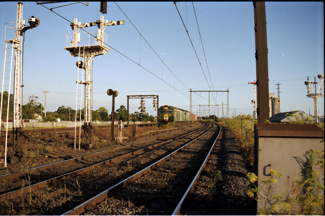 124-15
Sunshine looking from the passenger lines across to the Independent Through Goods lines, signal post 71 at camera, disc and semaphore signal posts 31 and 31B for control of the Independent Trough Goods lines, down Adelaide broad gauge goods train waiting to cross over the passenger lines, BL classes BL 30 Clyde Engineering EMD model JT26C-2SS serial 83-1014 and BL 35 Clyde Engineering EMD model JT26C-2SS serial 83-1019 in AN livery, standard gauge Sunshine Loop to the left of train, Newport Loop Line and GEB sidings at far right
