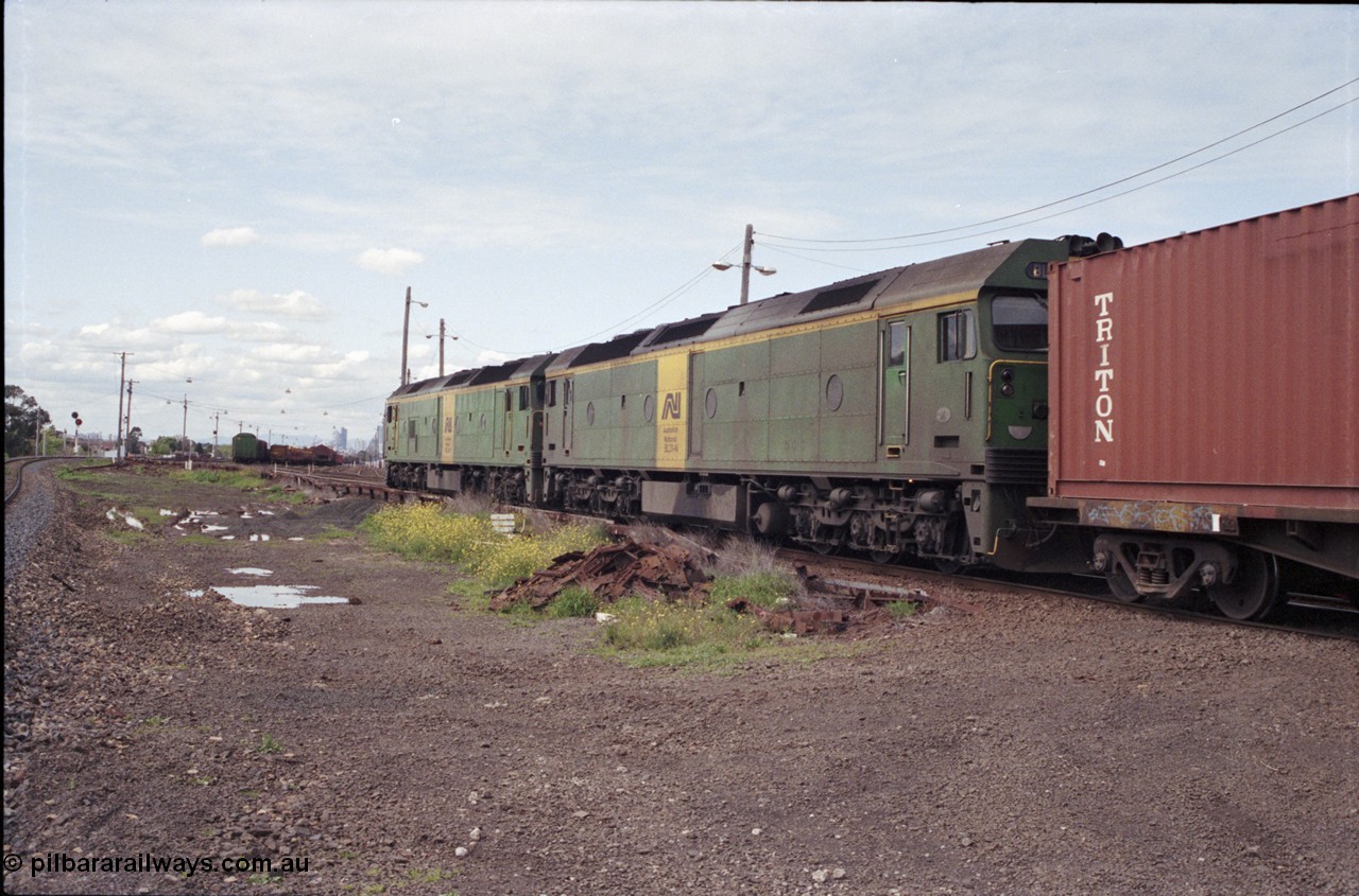 126-04
Tottenham yard, broad gauge Australian National BL class locos BL 29 Clyde Engineering EMD model JT26C-2SS serial 83-1013 and BL 31 serial 83-1015 lead up Adelaide goods train 9150 into Tottenham yard, standard gauge line on the left edge of image, looking towards Tottenham Yard, Melbourne skyline in background.
Keywords: BL-class;BL31;Clyde-Engineering-Rosewater-SA;EMD;JT26C-2SS;83-1015;