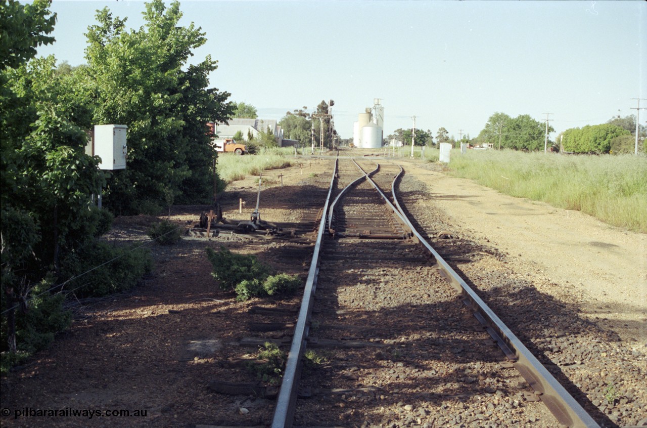 127-34
Elmore yard overview, looking towards Melbourne, points, point lever and interlocking facing up trains, near 207 km post, station building beyond grade crossing, silos in distance.
