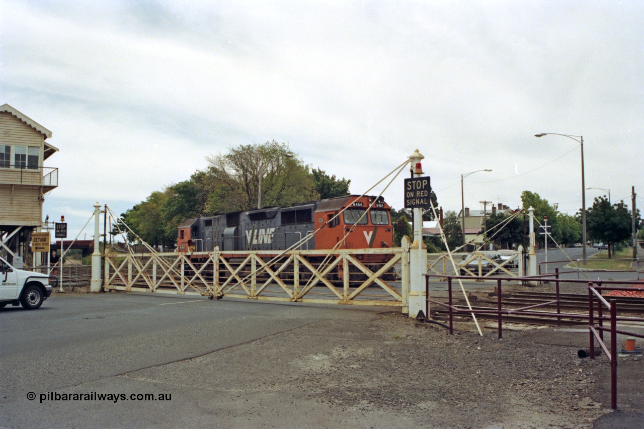128-16
Ballarat Station, Lydiard St or B signal box, view across Lydiard Street grade crossing with interlocked gates closed, V/Line broad gauge N class N 464 'City of Geelong' Clyde Engineering EMD model JT22HC-2 serial 86-1193 shunts back along No.2 Rd crossing Lydiard Street.
Keywords: N-class;N464;Clyde-Engineering-Somerton-Victoria;EMD;JT22HC-2;86-1193;