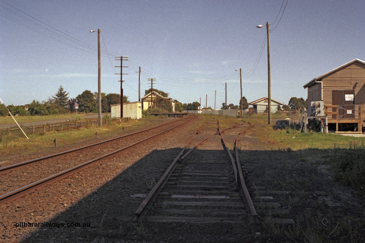 129-1-37
Koo Wee Rup station overview, shows removed track, looking in the up direction towards Melbourne, goods shed fenced off, gangers trolley shed at left in front of station building and platform. [url=https://goo.gl/maps/MChmwk7sx8yYrrxR7]Location is here[/url].
