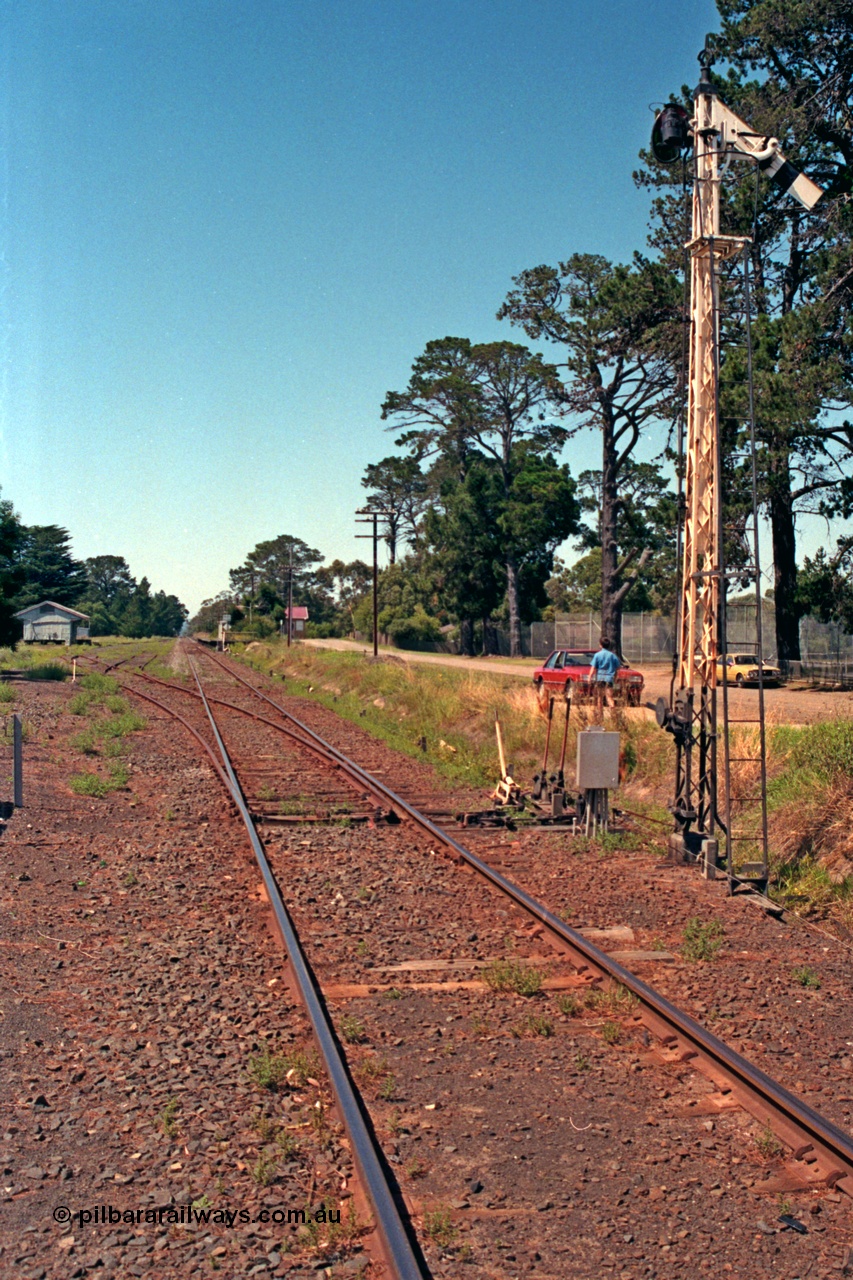 129-2-07
Lang Lang station yard overview, looking in the down direction towards Nyora from Melbourne end of yard, points and points and signal levers with interlocking, semaphore signal post, goods shed and station in the background.

