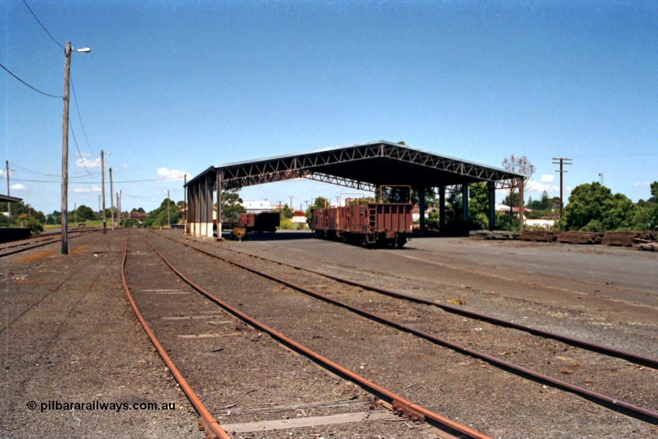 129-2-19
Korumburra station yard overview, showing Freightgate canopy, sleeper waggons, goods shed behind, looking in the down direction.
