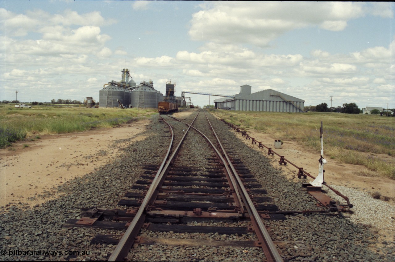 131-1-25
Burraboi station yard overview, looking south from Balranald end, points and derail lever, rice storage complex on the right, new Aquila silo complex on the left, grain waggons.
