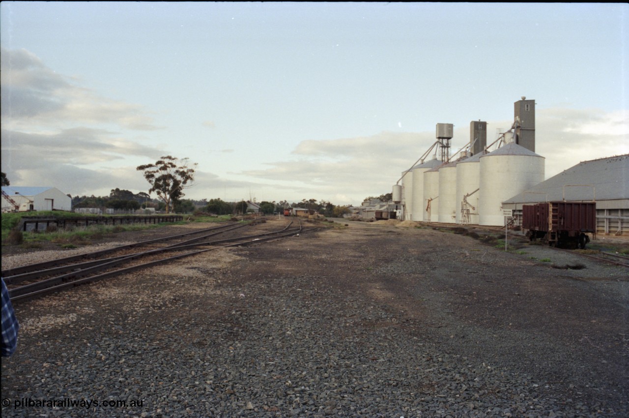 136-24
Deniliquin station yard overview looking north from Wood St, loading ramp and platform, RT can be seen in the background at the station building, grain sheds, Ascom silo complex, Victorian Oats Pool shed and VZTX class sleeper carrying waggon.
