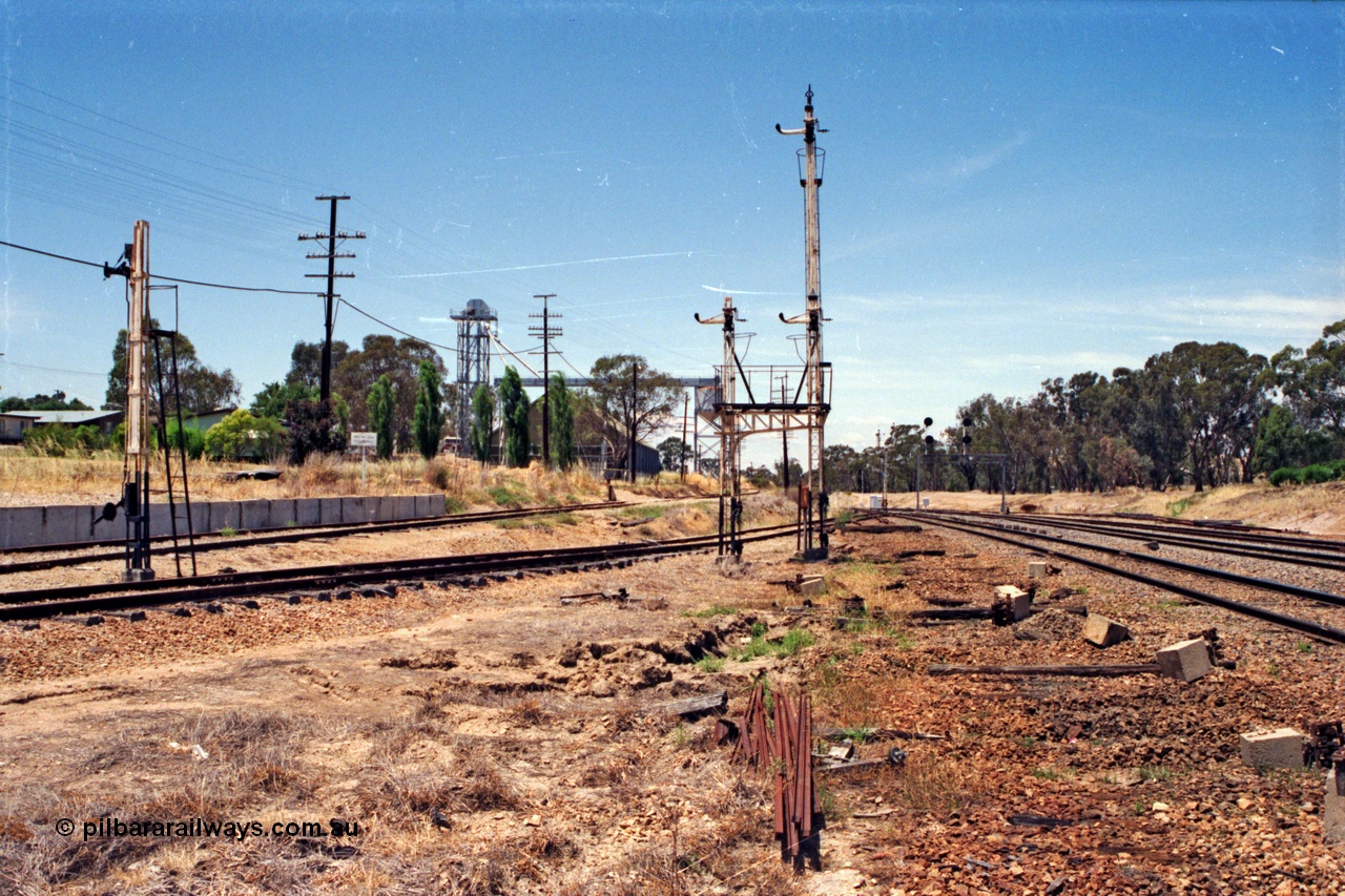137-1-21
Glenrowan looking north, with all the interlocking having been decommissioned some moths ago, the platform road has been removed, with just the mainline and standard gauge loop remaining. From the far right of the image is the standard gauge loop, then the broad gauge mainline. From where the image was shot is the platform or No.2 Rd, with the goods loop at left with the siding leading up the embankment to the former stock race, now a grain receival site. The remains of disc signal post 8 and semaphore post 7 (with co-acting arms) and a pile of point rodding are in the middle of frame.
