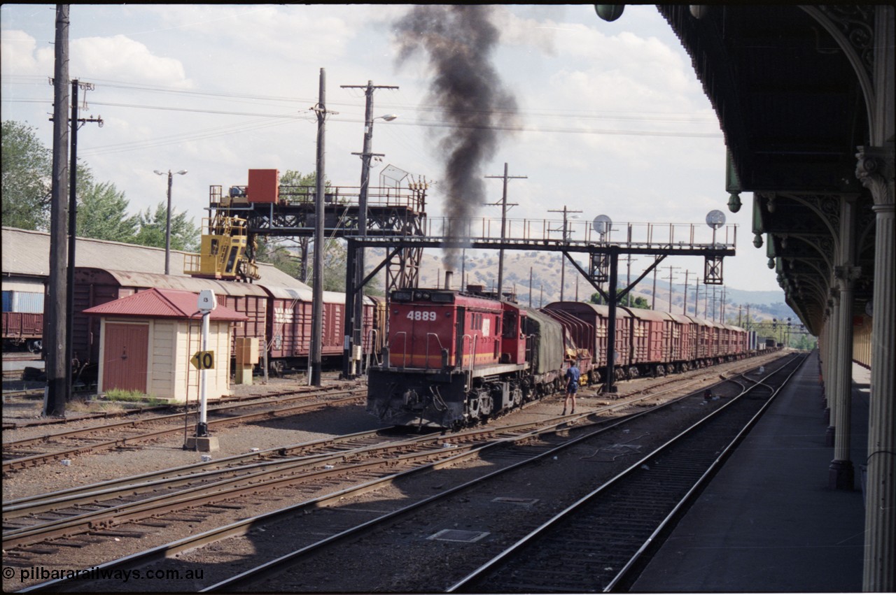 137-2-11
Albury station yard overview, standard gauge NSWSRA candy liveried 48 class 4889 AE Goodwin ALCo model DL531 serial G3420-4 shunts an arrival from Melbourne, the broad gauge 'trans-shipping yard' is to the left of the louvre vans, and a broad gauge track is directly to the left of the loco, ALCo smoke, signal gantry, station platform, shunter on ground.
Keywords: 48-class;4889;AE-Goodwin;ALCo;RSD-8;DL531;G3420-4;
