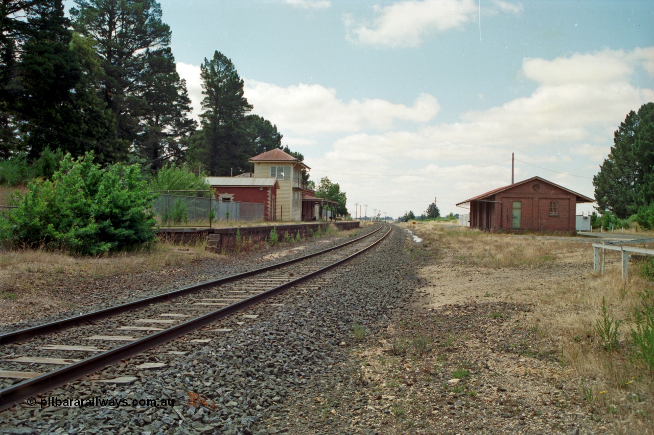 139-02
Creswick station yard overview, gang camp ATCO dongas, siding visible in the grass with baulk, brick goods shed, looking south from the north end, elevated signal box.
