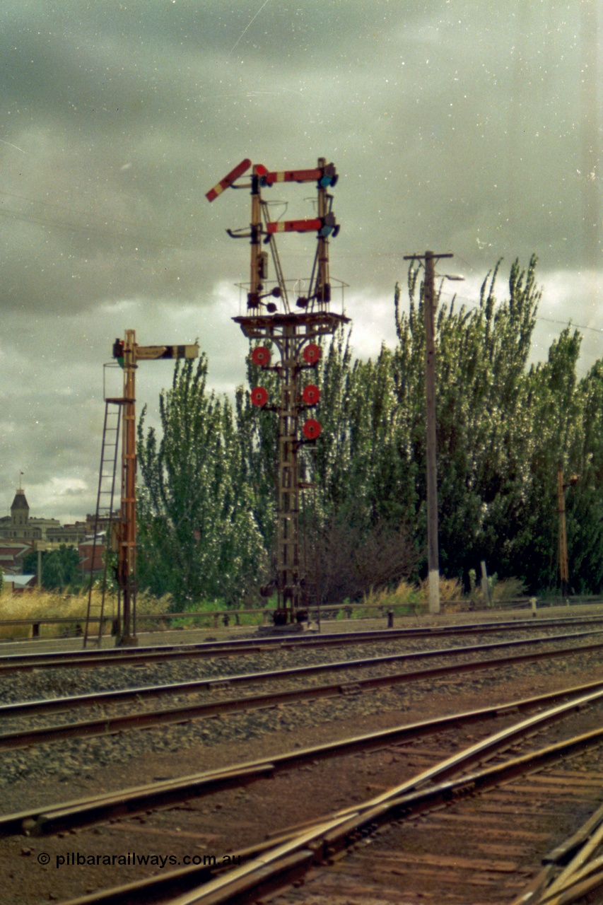 139-11
Ballarat yard, semaphore and disc signal Post 11 with rear facing semaphore signal post 9B, the top left hand Arm is the Down Home to Post 21 for No. 1 Road and is pulled off for an arriving passenger train. Top right hard Arm is the Down Home to Post 23 for No. 3 Road, bottom right Arm Down Home to Post 20 for No. 4 Road. Discs are all From 'U', top left to Car Sidings, centre left Disc towards Post 21 for No. 1 Road, bottom left Disc towards Post 22 for No. 2 Road, top right Disc towards Post 23 for No. 3 Road, centre right Disc towards Post 20 for No. 4 Road and the right bottom Disc to No. 5, 6 or 7 Roads.
