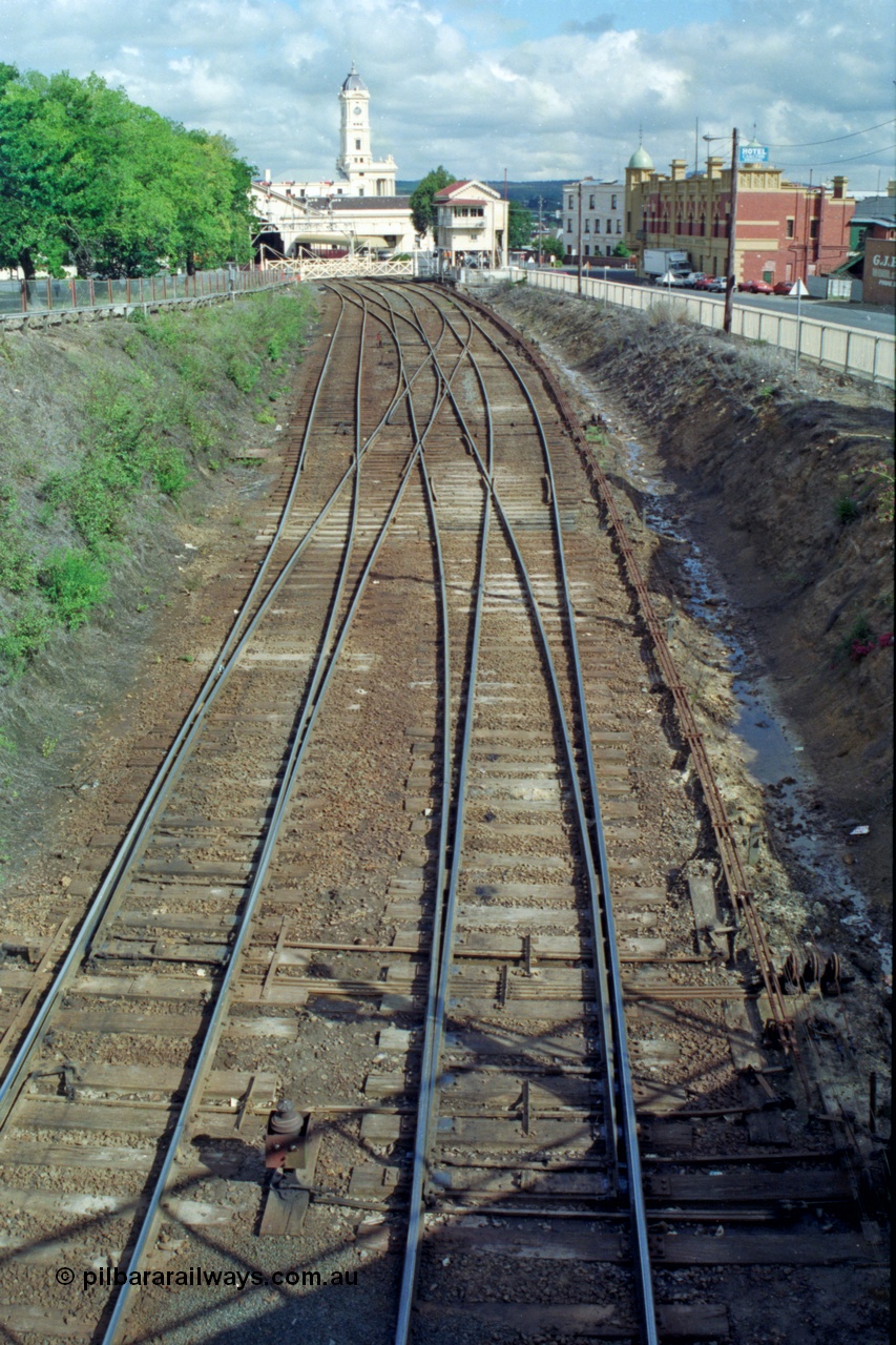 139-16
Ballarat station junction, track view of the junction at Ballarat B signal box or Lydiard Street box, looking east from the Armstrong Street bridge, double track to triple track which used to then become four tracks on the other side of the gates before No. 2 Road was removed. The shadow of Disc Post 33 can be seen along with the interlocking of the points with the signal pulleys.
