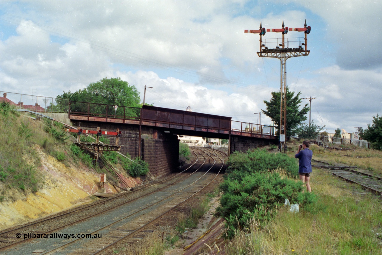 139-17
Ballarat, looking towards Lydiard St from Armstrong St bridge, semaphore signal Posts 30 and 30A, 30A are 'co-acting' signals for Post 30, operated from Ballarat Signal Box B at Lydiard St, this junction goes from double track to triple and used to be four roads through the station building. The manual interlocked gates of Lydiard St are just visible through the road overbridge. Left hand Arm Up Home Up Line to 'A' to Post 29 for No. 4 Road, middle Arm Up Home Up Line to 'B' to Post 27 or 28 for No. 3 or 2 Roads and the right Arm Up Home Up Line to 'C' to Post 26 for No. 1 Road.
