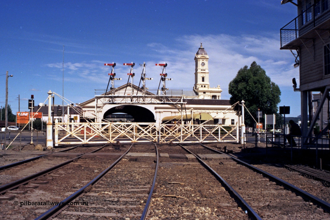140-1-17
Ballarat station overview, station building clock tower and canopy, looking across Lydiard St with interlocked gates and semaphore signal gantry, Ballarat B signal box is at right.
