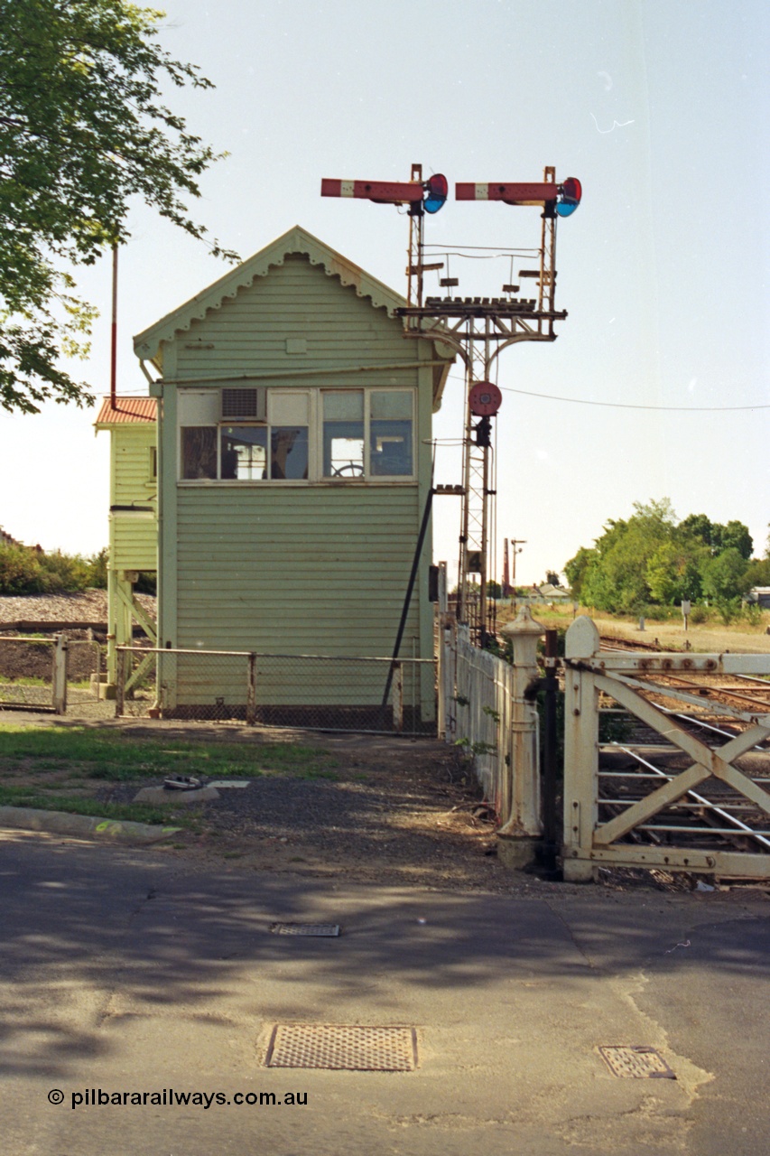 140-1-24
Ballarat North or C Signal Box, looking west, semaphore signal post 4, left arm is the Down Home to Ararat line, right arm is Down Home Maryborough line, and the disc is for the workshops sidings, the wheel for the interlocked swing gates can be seen in the window of the signal box.
