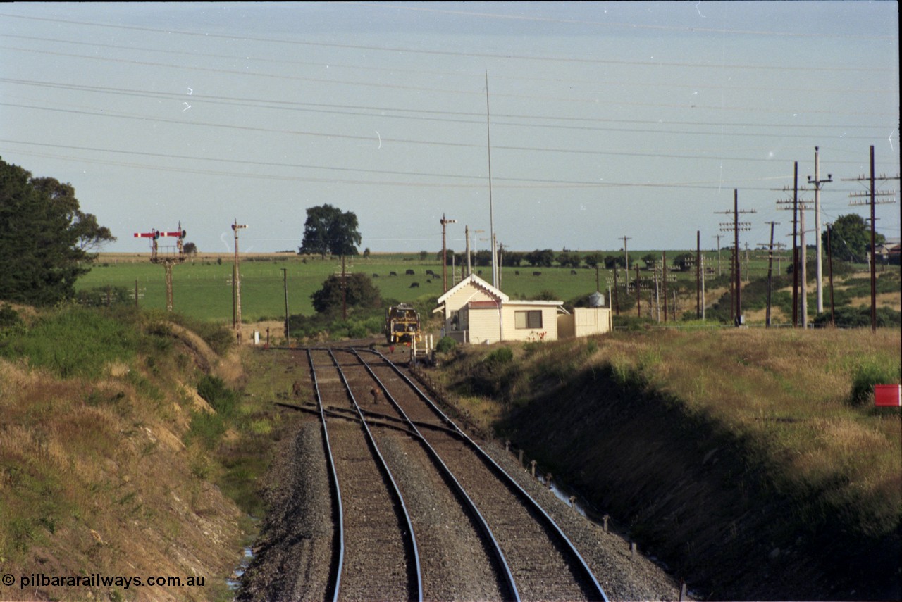 140-2-08
Warrenheip, station overview looking south, semaphore signal post 11 with co-acting up home semaphore arms, the signal pulled off is the down starting semaphore, the line to Melbourne (direct) curves to the left and the Geelong line around to the right.
