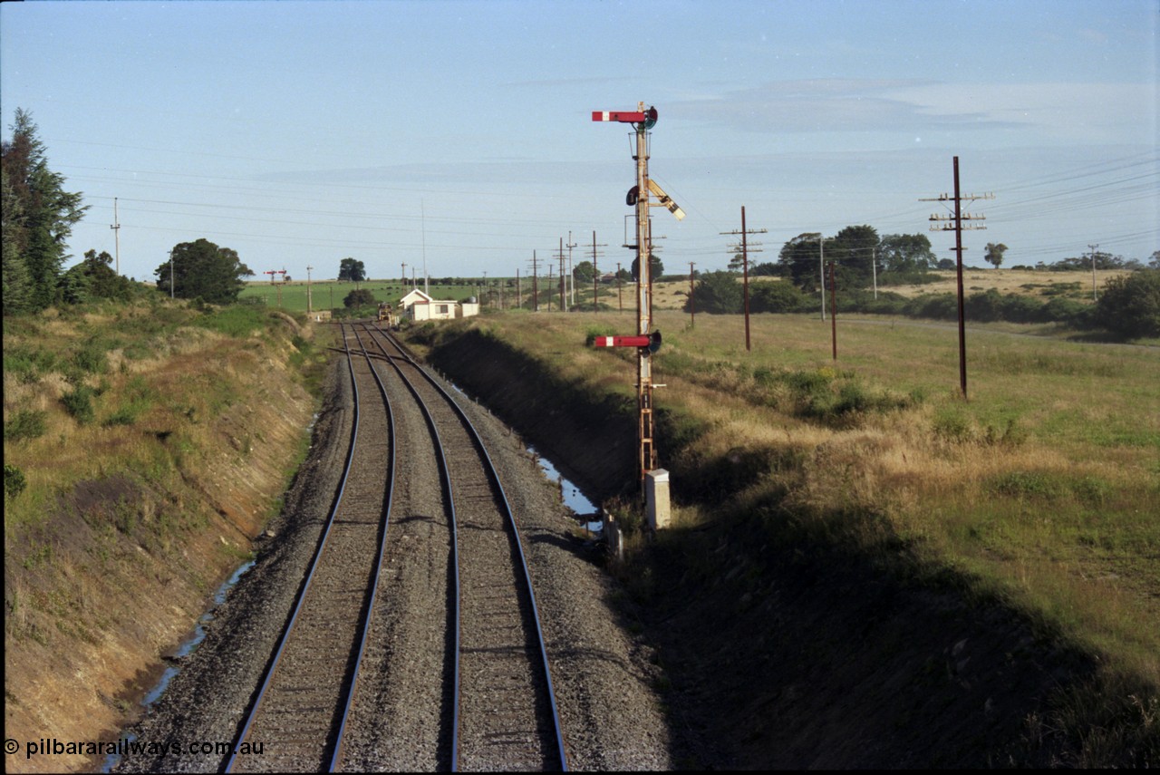 140-2-09
Warrenheip, station overview looking south, Melbourne line curves to the left and the Geelong line to the right, the Tamper track machine is in Siding A, the points and crossing lead to Siding B, signal box, staff exchange platform, notice how high the semaphore signal posts are.
