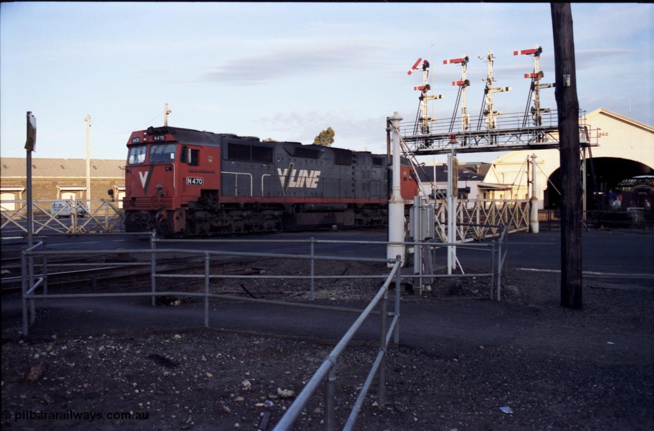 140-2-14
Ballarat station, V/Line broad gauge N class N 470 'City of Wangaratta' Clyde Engineering EMD model JT22HC-2 serial 86-1199 crosses Lydiard Street as it runs round the carriage set, through the interlocked gates and under the signal gantry on No.4 Rd, semaphore signal post 29 is pulled off for the move, this signal is controlled from A Box, while the signal is across the road from B Box.
Keywords: N-class;N470;Clyde-Engineering-Somerton-Victoria;EMD;JT22HC-2;86-1199;