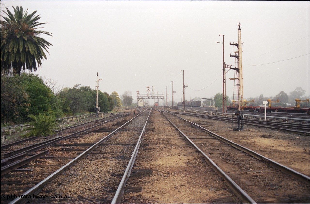 142-1-18
Benalla station yard overview looking south, disc signal posts 31 on the left and 32 on the right stripped, Siding Z at left, crossovers removed, Benalla B signal box and 9303 stabled goods in the background, rail recovery rake at right.
