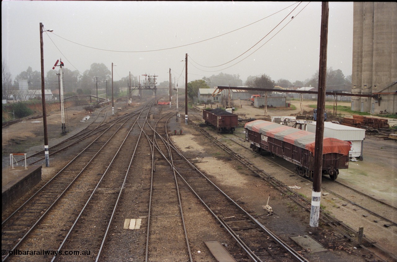 142-2-02
Wangaratta station yard overview looking south from footbridge, semaphore signal post 12 pulled off for up train, fuel siding is visible on the left, standard gauge line is in the cutting at far left, signal gantry in the distance, V/Line VOCX and VOFX type bogie open waggons at right.
Keywords: VOCX-type;VOFX-type;