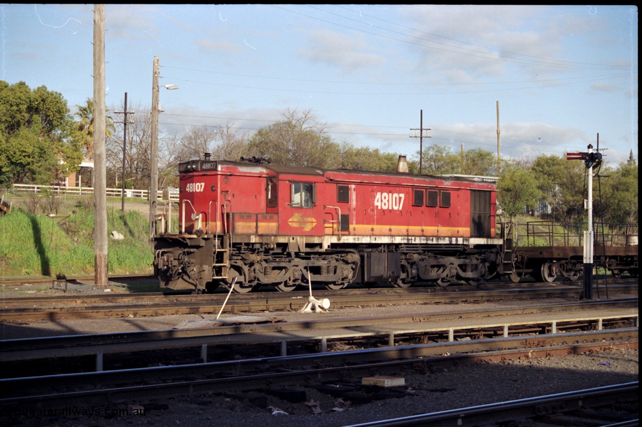 142-3-07
Albury loco depot, yard shunter, standard gauge NSWSRA candy liveried 48 class 48107 AE Goodwin ALCo model DL531 serial G3420-22 with shunters float rests between shunt jobs on Sunday afternoon, semaphore signal, point lever, point rodding under metal walkway.
Keywords: 48-class;48107;AE-Goodwin;ALCo;DL531;G3420-22;