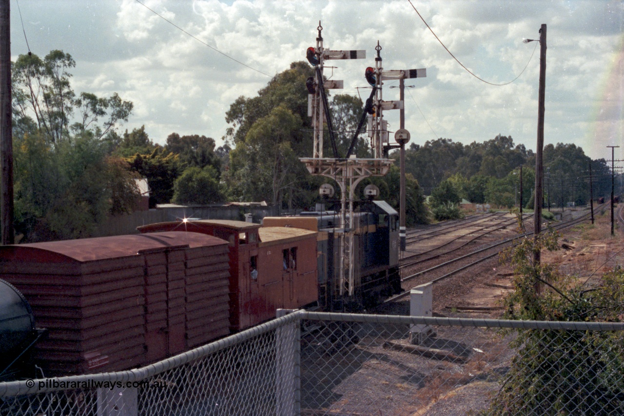 143-09
Wangaratta, down Wahgunyah Special 'Stringybark Express' departs up home semaphore past signal Post 23 with broad gauge VR liveried Y class Y 133 Clyde Engineering EMD model G6B serial 65-399, leading ZL type six wheel guards van ZL 2, U type four wheel louvre van U 892 and WT type four wheel water tank WT 236, sidings in the background are extensions of 3, 4 and 5 Roads, the Rowan Street underpass is visible beyond along with the Ovens River bridge.
