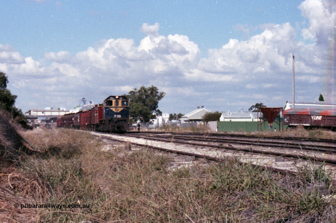 143-25
Wahgunyah, broad gauge VR liveried Y class Y 133 Clyde Engineering EMD model G6B serial 65-399 leads the arriving 'Stringybark Express' mixed special into the yard past the V/Line VOFX type bogie super phosphate waggons and sheds on the right, Uncle Tobys in the background.
Keywords: Y-class;Y133;Clyde-Engineering-Granville-NSW;EMD;G6B;65-399;