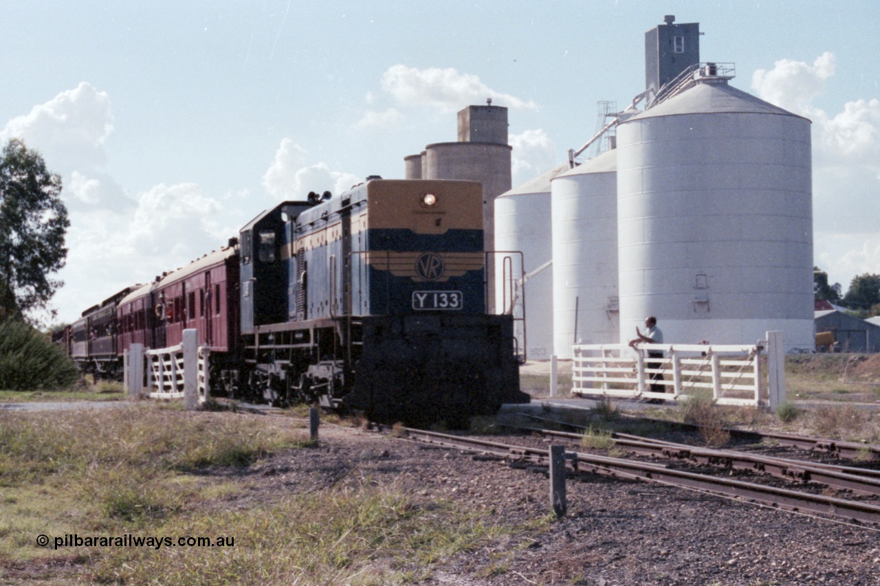 143-36
Rutherglen, up Wahgunyah 'Stringybark Express' mixed special under the power of VR liveried broad gauge Y class Y 133 Clyde Engineering EMD model G6B serial 65-399 crosses Howlong St through the non-interlocked hand swing gates as the Williamstown and Ascom style silos stand sentinel and the signaller gives a wave.
Keywords: Y-class;Y133;Clyde-Engineering-Granville-NSW;EMD;G6B;65-399;