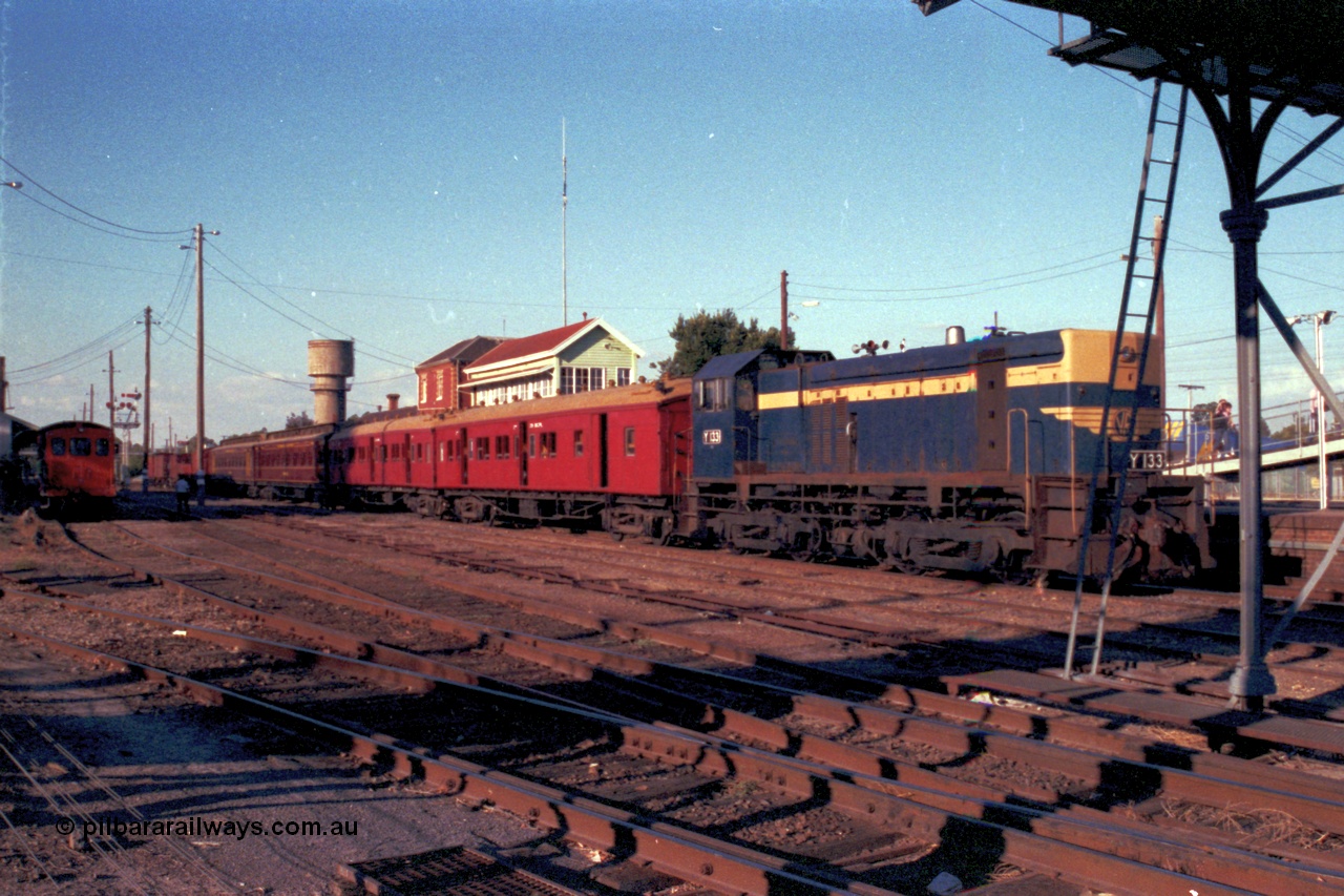 144-09
Wangaratta yard view, Victorian Railways liveried broad gauge Y class Y 133 Clyde Engineering EMD model G6B serial 65-399 holds the up Wahgunyah mixed special the 'Stringybark Express' in No. 2 Rd while V/Line rail tractor RT class RT 5 looks on from No. 5 Rd. The water tank in the background is the town water supply, the railways tank is just visible on the left edge of shot.
Keywords: Y-class;Y133;Clyde-Engineering-Granville-NSW;EMD;G6B;65-399;