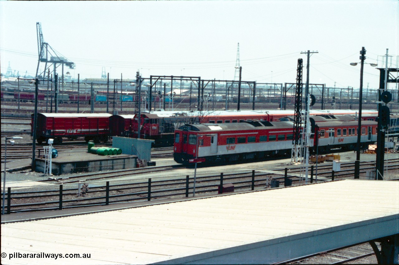 145-02
Spencer Street Station, Melbourne Yard overview towards Melbourne Port shows rail cars, passenger carriages and shunt loco with view across goods yard with DRC, MTH, D van and Y classes all present, Port of Melbourne container crane in distance.
