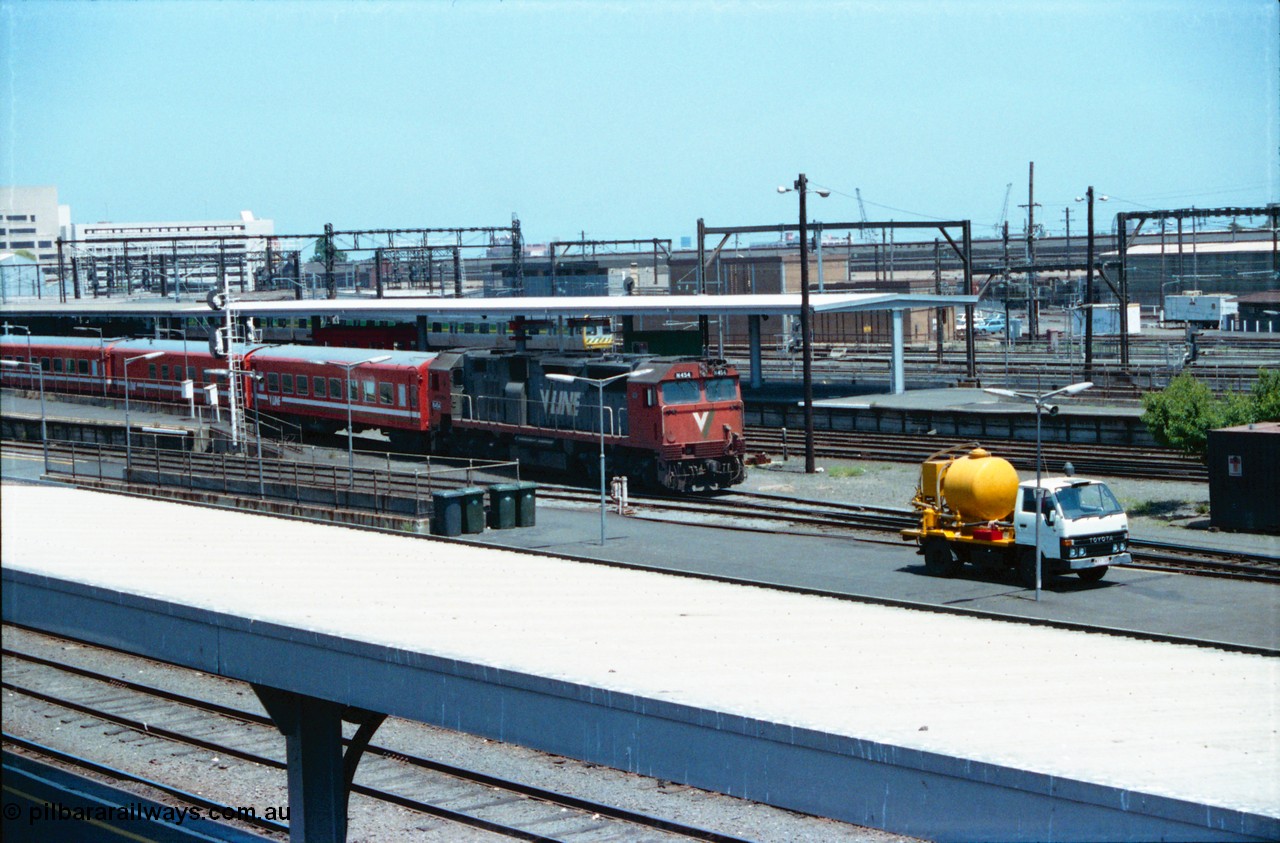 145-03
Spencer Street Station overview, broad gauge V/Line N class N 454 'City of Horsham' Clyde Engineering EMD model JT22HC-2 serial 85-1222 departs with a carriage set, a suburban Met coloured Comeng spark in the background, septic tank pump truck in foreground.
Keywords: N-class;N454;Clyde-Engineering-Somerton-Victoria;EMD;JT22HC-2;85-1222;