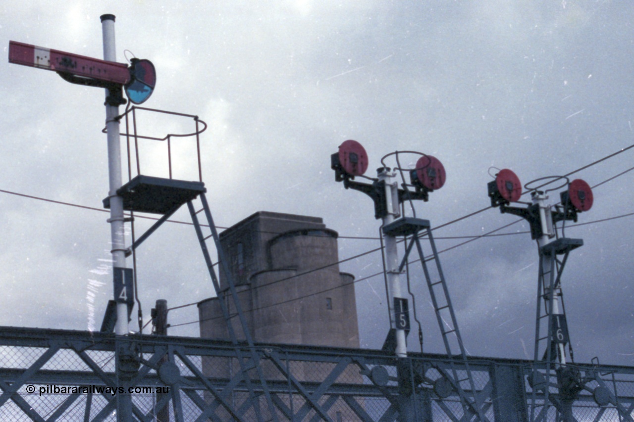 148-11
Wangaratta, signal gantry on foot bridge with semaphore signal post 14 and twin disc signal posts 15 and 16. Post 14 is the Up Home Signal from No.2 Road to 'A' to Post 9. Post 15 are both Up Signals, Left-hand Disc from No. 3 Road to 'A' towards Post 9, Right-hand Disc from No. 3 Road to Sidings 'H' or 'E'. Post 16 are both Up Signals, Left-hand Disc from Nos. 4, 5 or 6 Roads to 'A' towards Post 9, Right-hand Disc from Nos. 4, 5 or 6 Roads to Sidings 'H' or 'E'.
