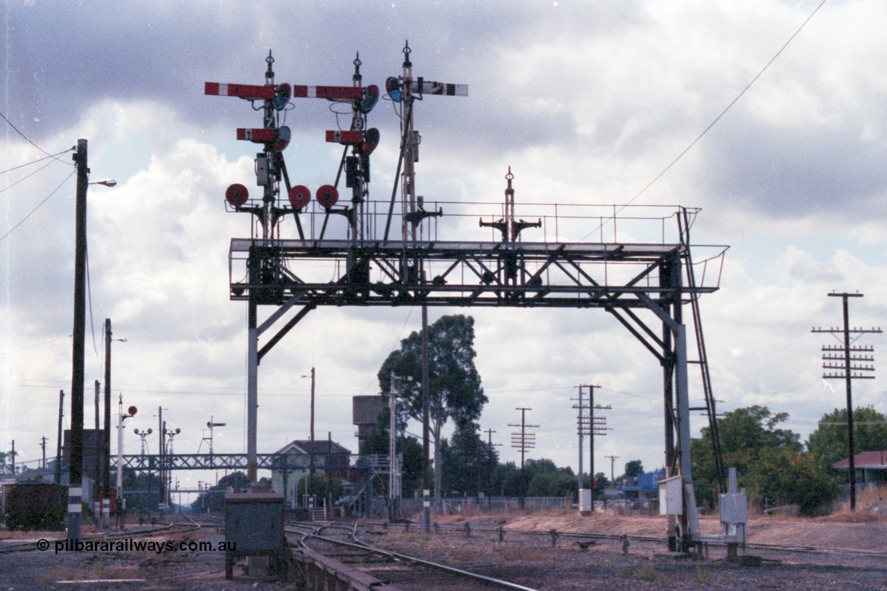 148-25
Wangaratta, Signal Bridge, Down Signal Posts 7, 8 and stripped 10 facing camera, Up Post 9 facing away. Signal Post 7 two arms and two discs, Top arm Home Signal 'A' to No.2 Road to Post 17, Bottom arm Calling-on Signal from 'A' to No. 2 Road towards Post 17. Left-hand Disc from 'A' to No. 4 or 5 Roads towards Post 19; or to No. 6 Road. Right-hand Disc from 'A' to No. 3 Road towards Post 17. Signal Post 8 two arms one disc, Top arm Home Signal from 'A' to No. 1 Road to Post 20, Bottom arm Calling-on Signal from 'A' to No. 2 Road towards Post 20. The Disc from 'A' to Carriage Dock. Stripped Disc Post 10 was from 'B' to No. 1 Road towards Post 20 and from 'B' to Carriage Dock.
