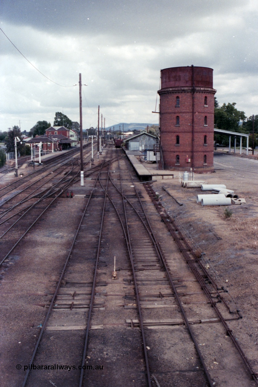 148-34
Wangaratta yard looking south (Up direction) from footbridge, from extreme left, Siding 'A', Signal Post 20 pulled off, Main Line or No. 1 Road, No. 2 Road, No. 3 Road, No. 4 Road and No. 5 Road, goods shed and platform and water tower with Freight Gate awning behind, point rodding and signal wires visible.

