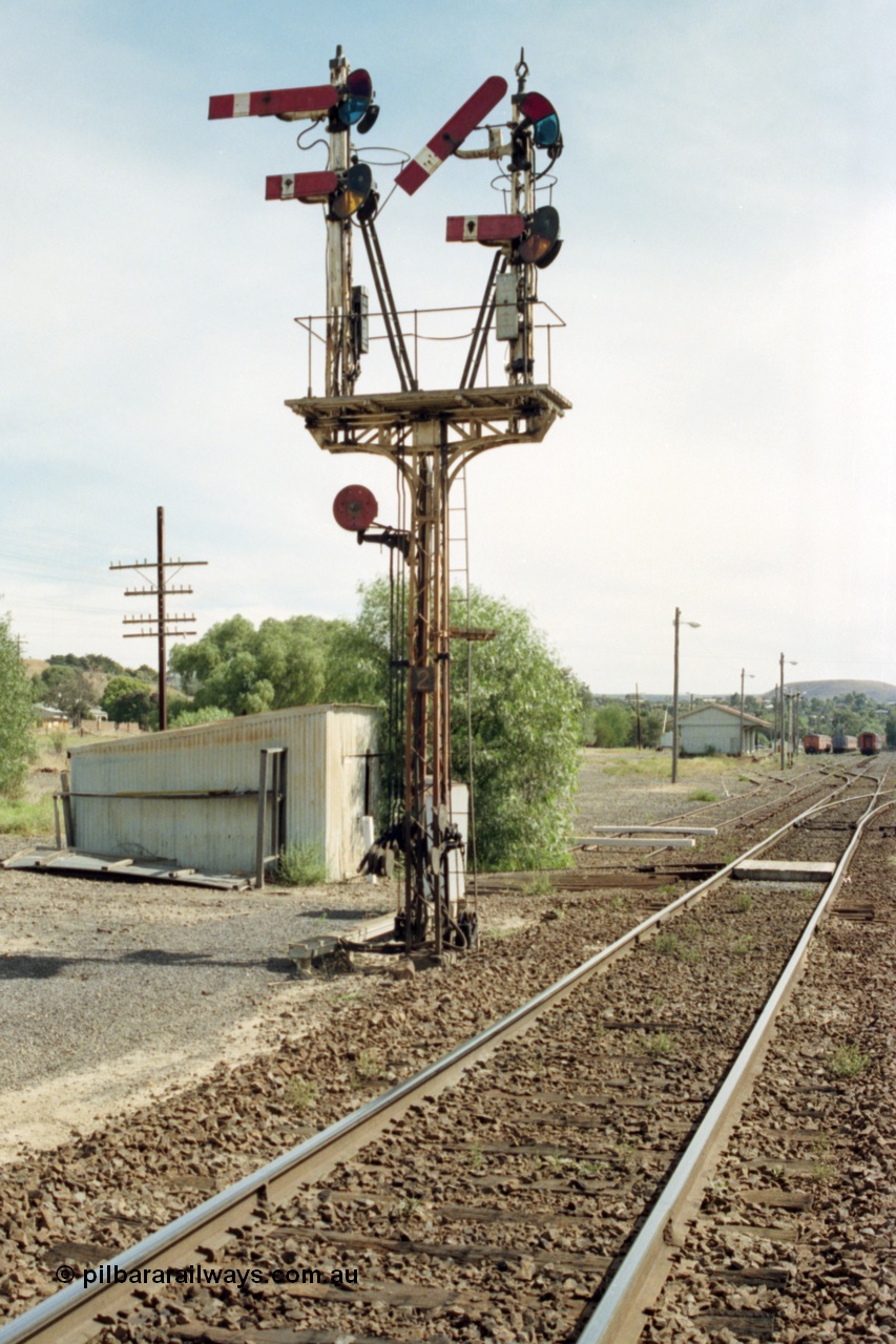 149-11
Bacchus Marsh down home signal post 2, with the signal pulled off for No.1 Rd or the platform road for a down Ballarat passenger train, gangers trolley shed is behind post and goods shed and stabled passenger sets in the background.
