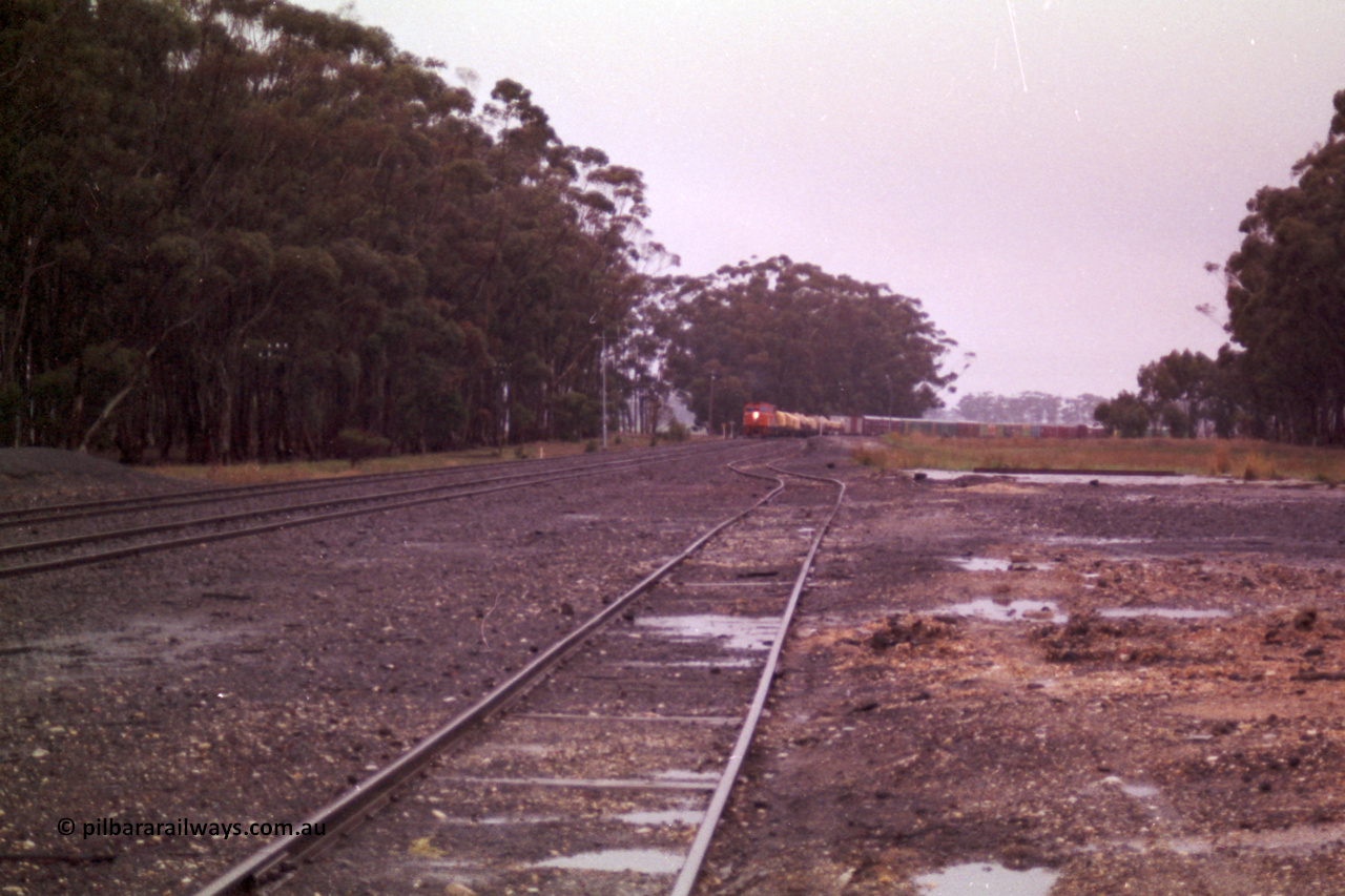 150-14
Lismore, station yard overview looking towards Melbourne from goods loading ramp, V/Line broad gauge C classes Clyde Engineering EMD model GT26C leading Adelaide bound goods train 9169 at the trailable points which are set for left hand lay.
