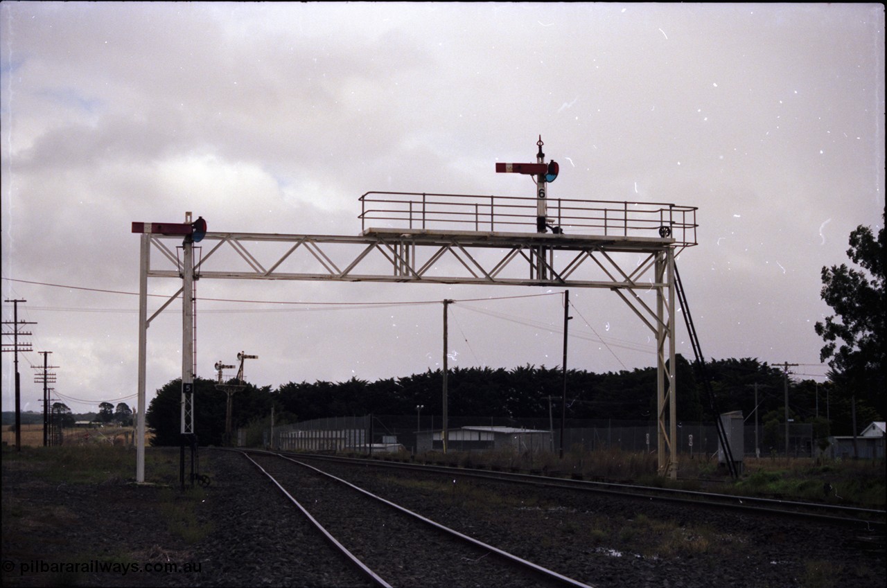 153-1-08
Ballan yard view looking towards Ballarat, signal gantry with semaphore post 6 for mainline moves, semaphore signal post 5 for the goods loop and semaphore signal post 7 up home, colour light signal post 10 in the distance.
