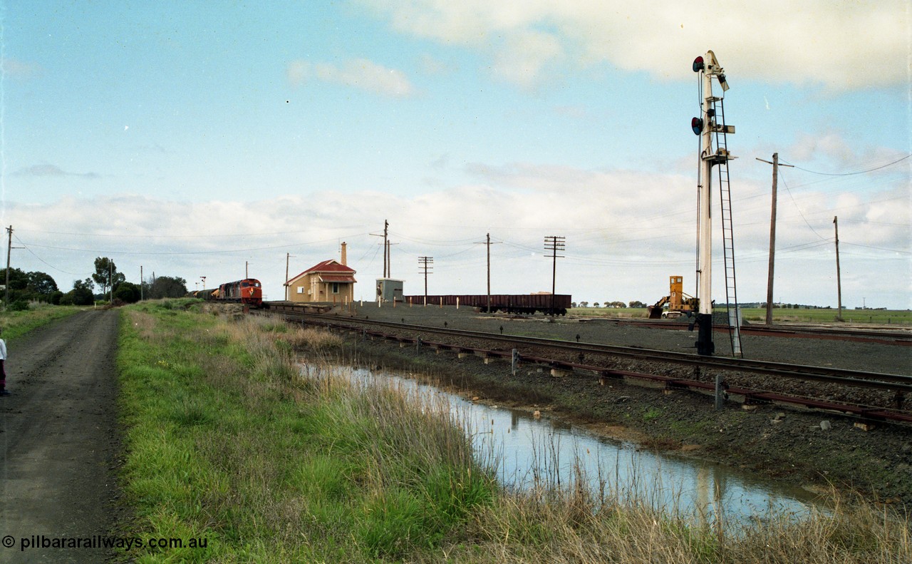 154-04
Gheringhap station yard overview, station building, shed, VOJF type bogie gypsum waggons, unloading contraption, semaphore signal pulled off for Maroona line, V/Line broad gauge goods train 9169 to Adelaide, via Cressy prepares to depart behind triple C class locomotives Clyde Engineering EMD model GT26C.
Keywords: C-class;C510;Clyde-Engineering-Rosewater-SA;EMD;GT26C;76-833;