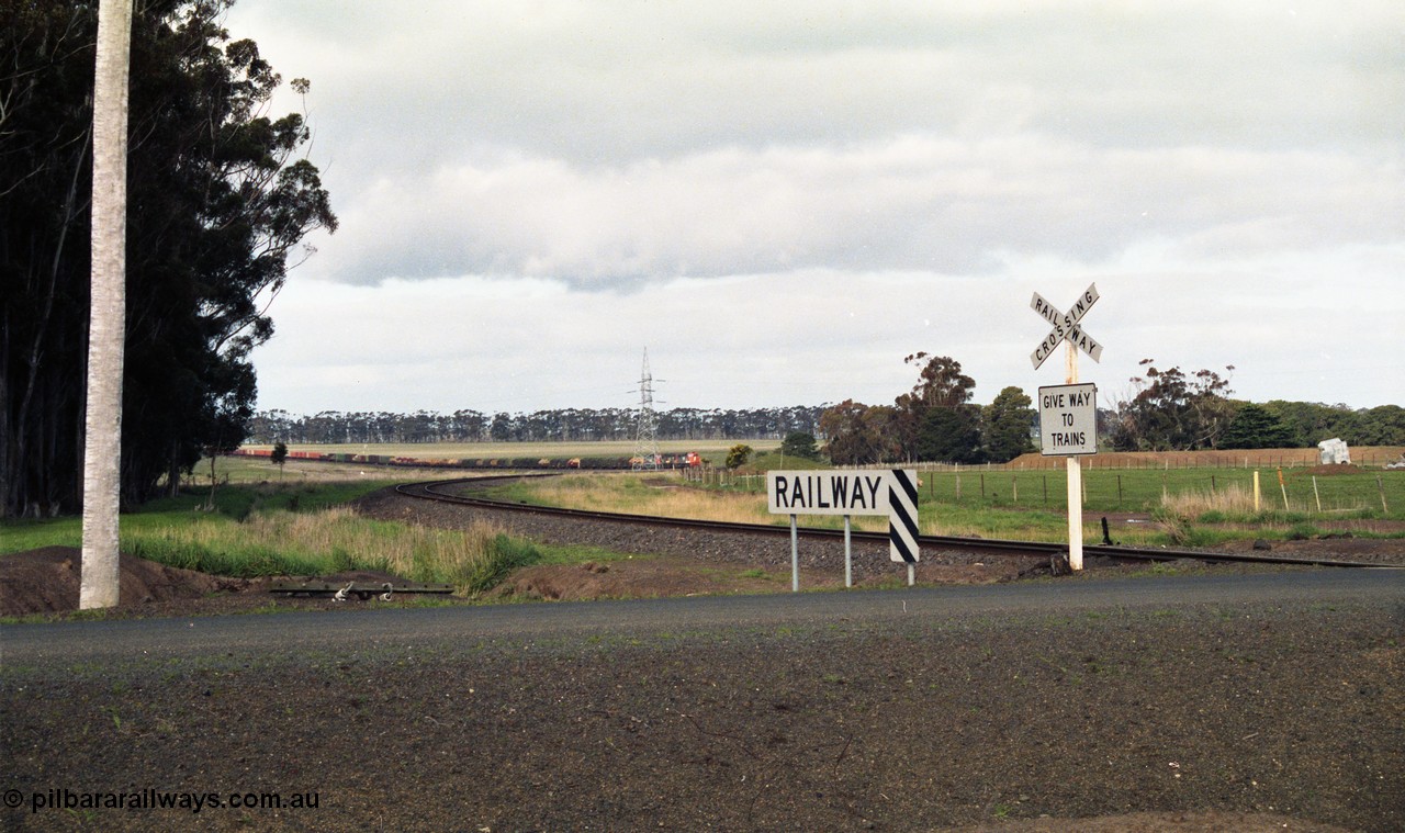 154-08
Lismore, track view looking back towards Geelong, broad gauge goods train 9169 in the valley, taken from Gnarpurt Road crossing.
