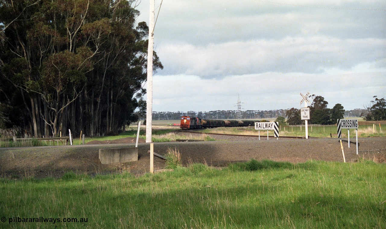 154-09
Lismore, track view looking back towards Geelong, V/Line broad gauge goods train 9169 on the curve behind triple C class locomotives Clyde Engineering EMD model GT26C, looking across Gnarpurt Road crossing.

