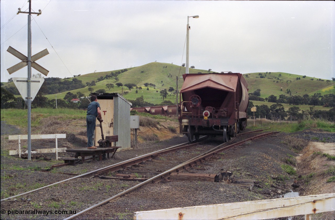 157-35
Kilmore East, Apex Quarry Siding, as the last waggon clears the points, the second person restores them to the reverse position before re-joining his train, handbrake end of VHQF type bogie quarry products waggon, end of train device, catch points and lever, telephone booth and grade crossing sign.
