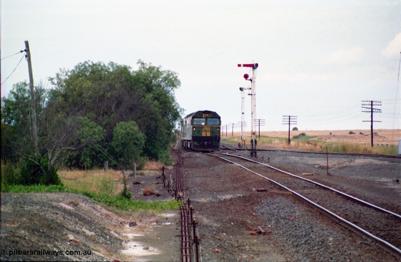 159-10
Gheringhap, track view looking east towards Geelong from the former No.2 platform, signal rodding running along edge of platform, semaphore signal post 3, Australian National broad gauge BL class BL 27 Clyde Engineering EMD model JT26C-2SS serial 83-1011 leads down goods train 9169 as it arrives on their way to Adelaide.
